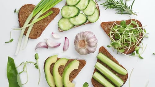 Sandwich with Avocado Cucumber Olives and Green Onions on a Wooden Board