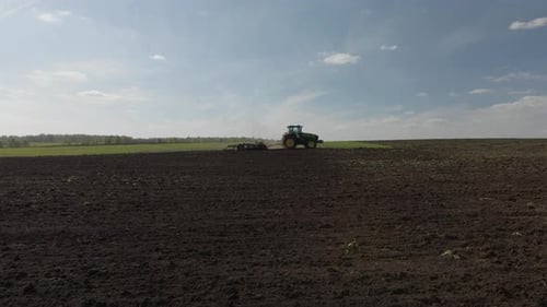 Agricultural green big tractor plows in the field.