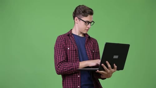Young Adult Using Laptop Against Green Background