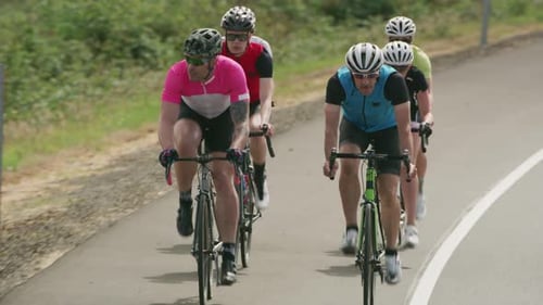 Tracking-Aufnahme einer Gruppe von Radfahrern auf einer Landstraße. Vollständig für den kommerziell Gebrauch freigegeben.