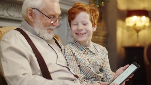 Grandfather and Grandson Enjoy Tablet Together Indoors