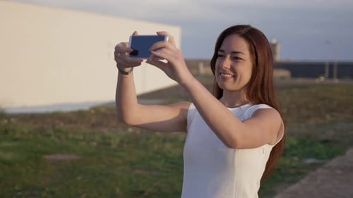Woman Takes Photos Near Beach During Golden Hour
