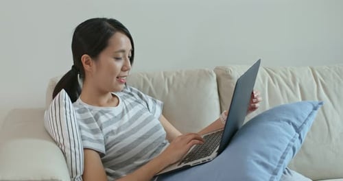 Smiling Woman Using Laptop on Sofa