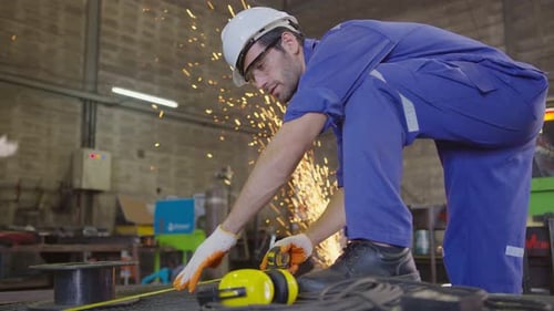 Man Using Power Tool Producing Sparks in Factory