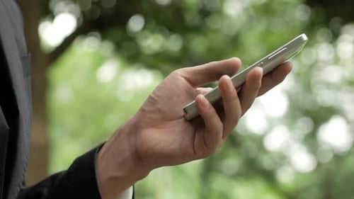 Hand Holds Smartphone in Green Outdoor Setting