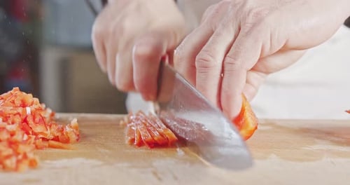 Slow motion close up of a chef knife slicing a Red bell pepper