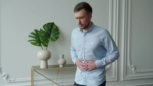 Man with Stomach Pain in Modern Home