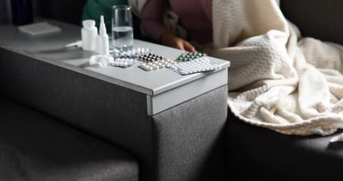 Sick woman with blister pack of pills and smartphone in hand using online pharmacy store