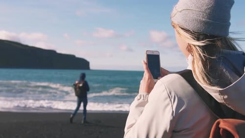 Young Loving Couple Taking Pictures on Smartphone on Beautiful Beach in Iceland During Sunset Slow