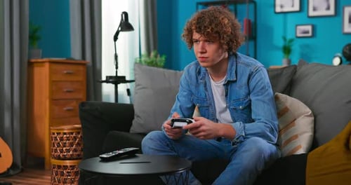 Teen Plays Video Game on Couch at Home