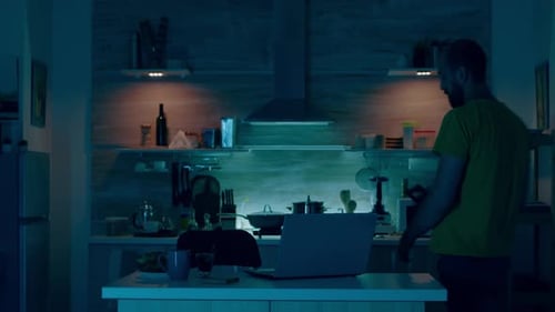 Man Typing on Laptop at Kitchen Island