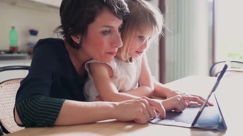 Woman and Child Using Tablet at Table Indoors