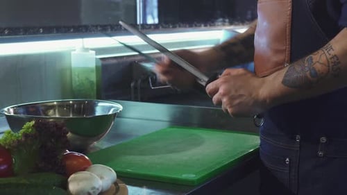 Person Sharpening Knife in Commercial Kitchen