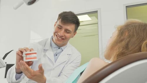 Friendly Dentist Explains Teeth Care to Young Patient