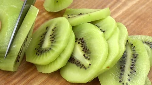 Slicing a Kiwi on a Wooden Cutting Board