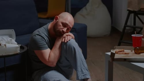 Man Sitting on Floor in Cluttered Home
