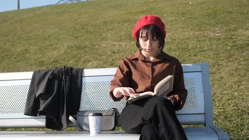 Young Woman Reading a Book on Park Bench