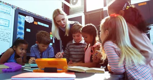 Teacher Helping Young Students with School Work