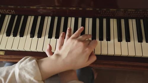 Hands Playing Keys of an Old Piano