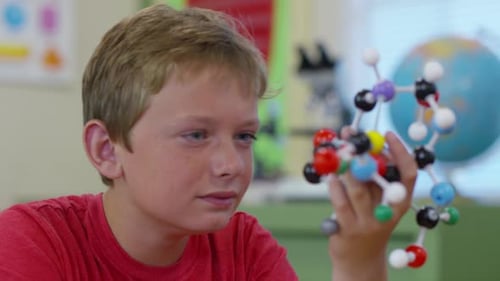 Young boy in school classroom building a molecule model in science class
