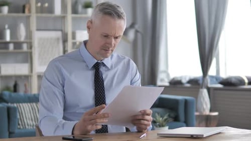 Adult Man Reviews Documents at Desk