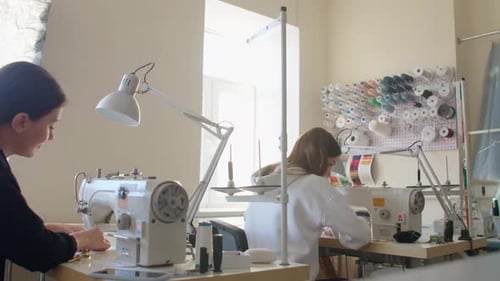 Two Women Seamstresses Working on Sewing Machines in the Tailoring Workshop of the Garment