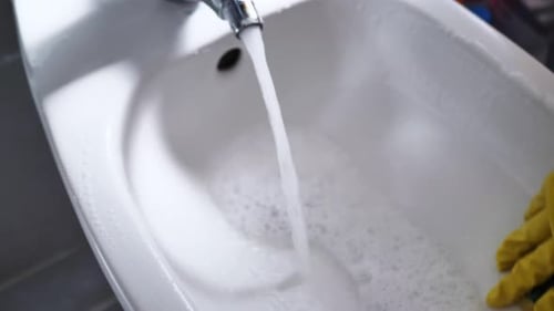 Hand Wipes Down Bidet with Sponge and Running Water