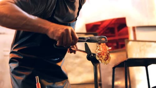 Glassblower Shaping Molten Glass in Workshop