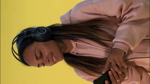 Woman Listens to Music on Headphones with Phone