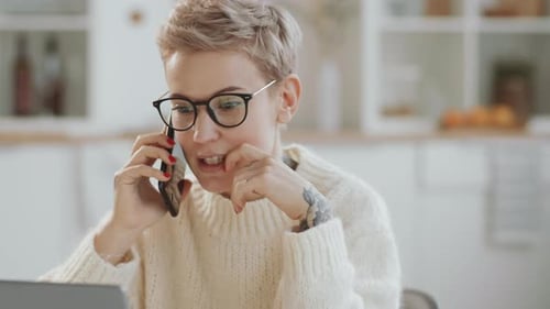 Woman Talking on Phone While Using Laptop at Home