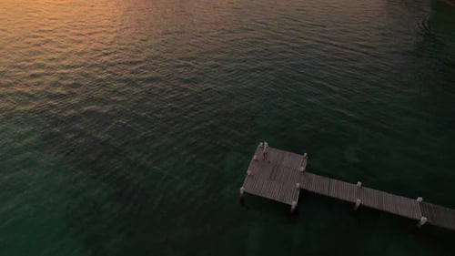 Drone Over Woman On Wooden Pier Over Green Ocean