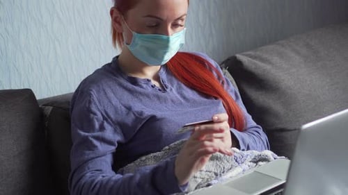 Woman with Mask Uses Laptop and Credit Card