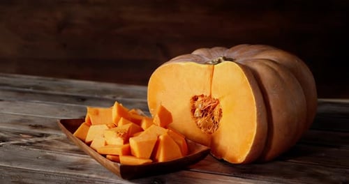 Halved Pumpkin with Cubed Pumpkin Pieces on Wooden Table