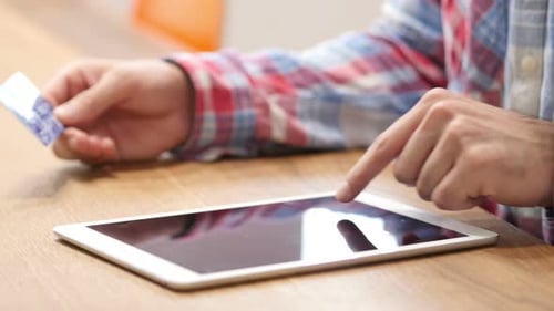 Man Uses Tablet with Credit Card on Table
