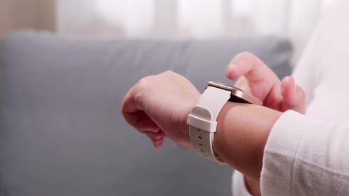 Close up shot of a woman hand who touch and scrolling on a smartwatch in order to quickly check appl