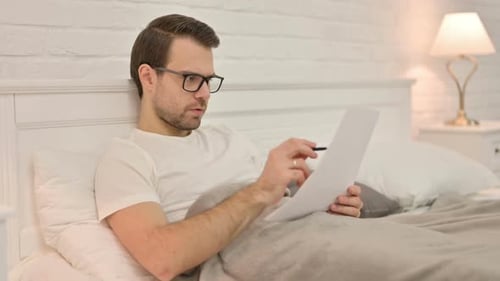 Man Reading and Writing in Bed at Night