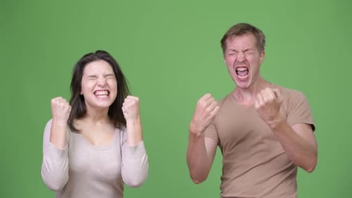 Young Couple Looking Excited Together Against Green Background