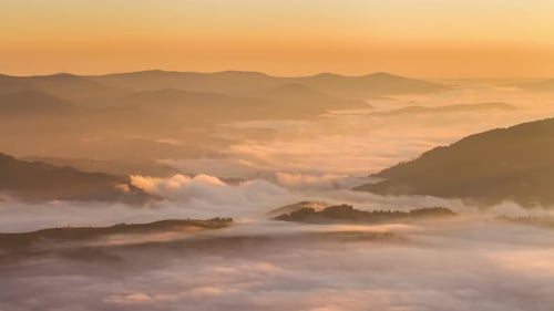 Sunrise over Mountain Peaks with Foggy Valley