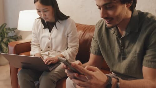 Man and Woman Using Technology Together on Couch