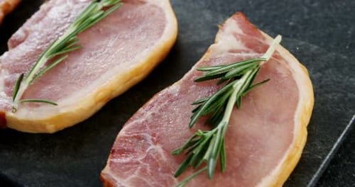 Raw sirloins arranged on the board with rosemary