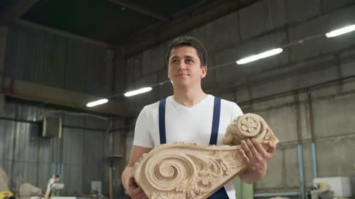 Artisan Holding Wood Carving in Workshop