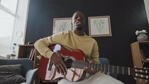 Man Plays Guitar and Gives Lesson Indoors