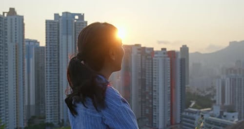 Woman look at the city with sunlight light flare at sunset time