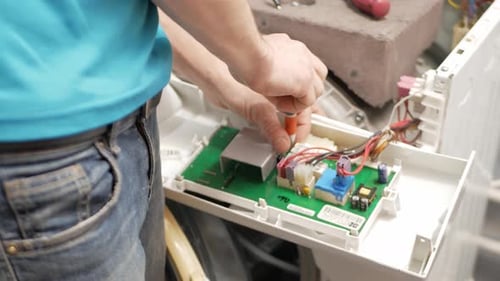 Man Repairing Circuit Board with Screwdriver