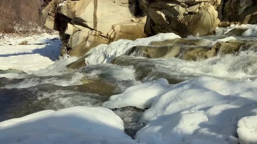 Medium Shot of Mountain River Flowing Rapidly Covered with Snow