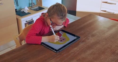 Girl Drawing With Stylus on Tablet at Table