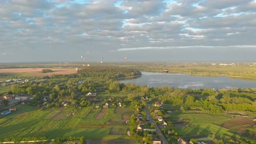 Hot Air Balloons Over Rural Lake Landscape