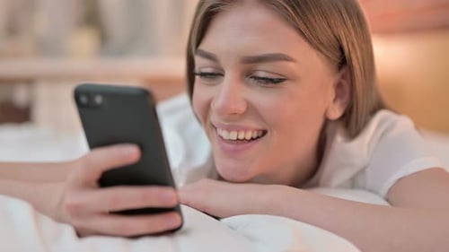 Close Up of Happy Young Woman Using Smartphone in Bed