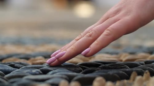 Hand Touching Smooth Stones in Close Up