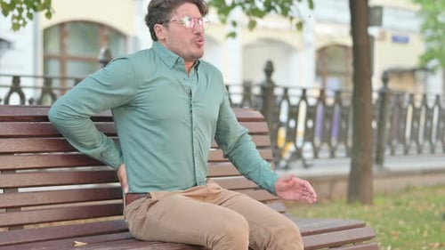 Man Experiencing Back Pain While Sitting on Bench